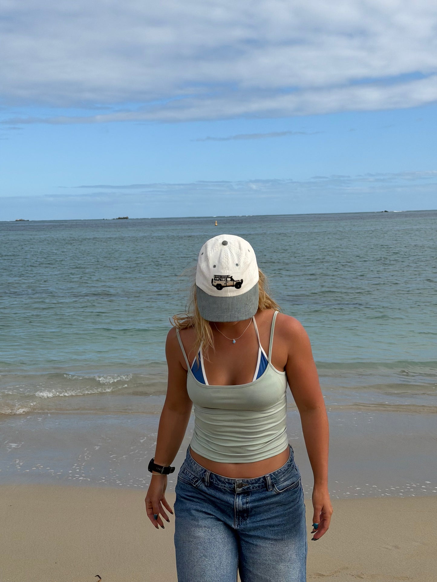 Troopy hat on beach with white crown, teal brim, and truck graphic.