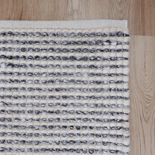 Handwoven floor rug with grey and cream looped texture and striped rows