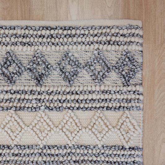 Handwoven floor rug with braided loop texture, blue and natural geometric accents