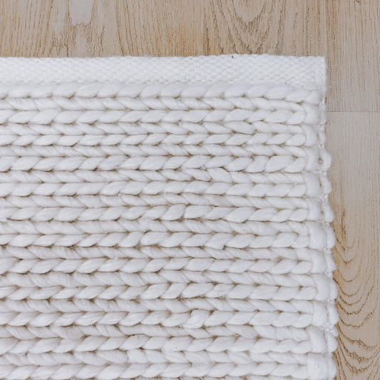 Handwoven white floor rug with thick braided rows and textured weave detail