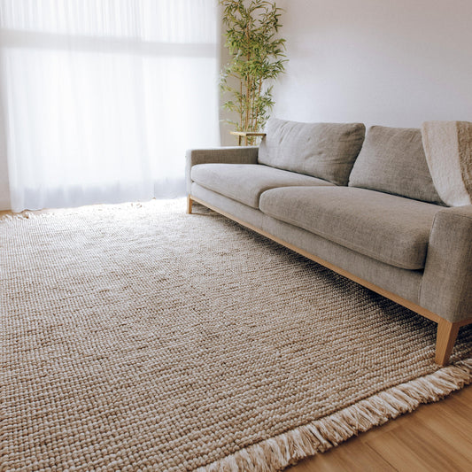 Amora handwoven floor rug, textured neutral weave with soft fringe along edge.