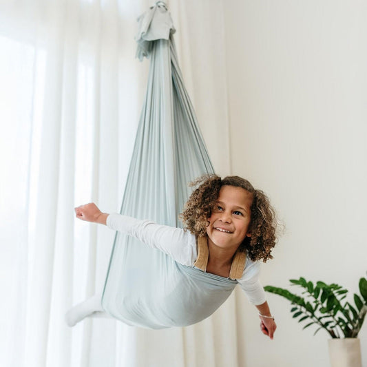 Light grey therapy swing cocoon with child inside, soft draped fabric and top hanging loop