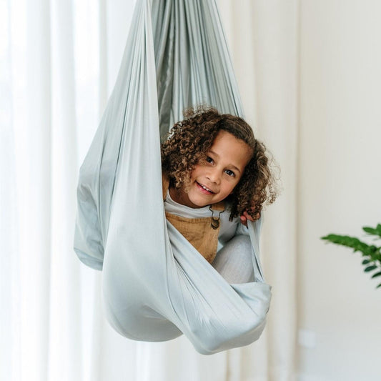 Light grey therapy swing cocoon wrap with child peeking, gathered drape and shoulder opening