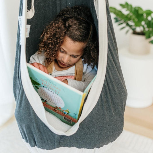 Charcoal hammock swing pod with white edge, child reading a book inside