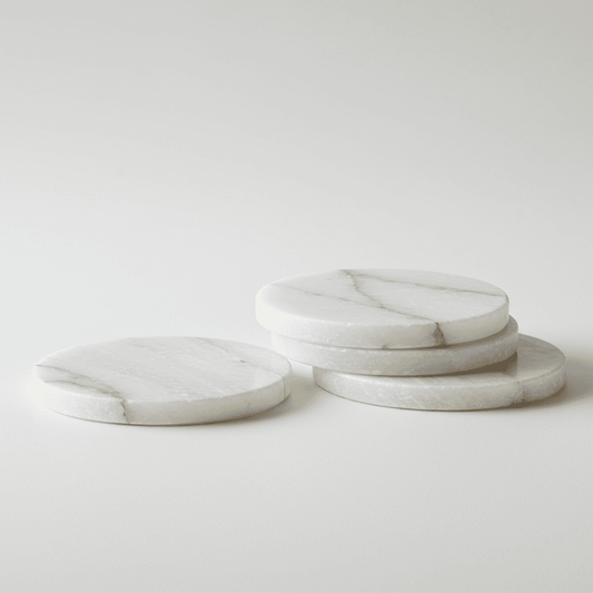 Round alabaster-style coaster set, light white stone with natural veining.