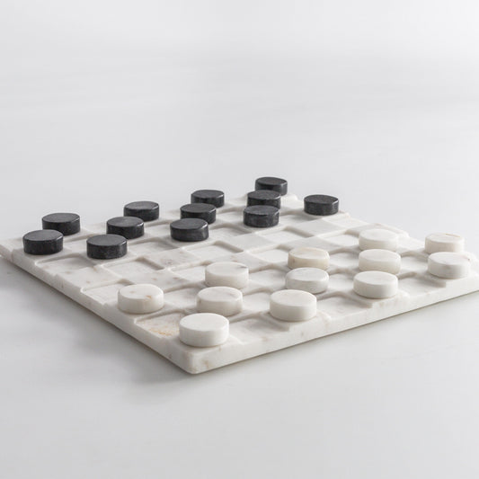 Marble checkers board with white squares and black round pieces on a marble grid
