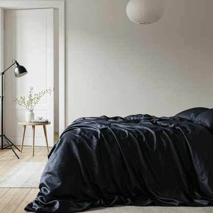 Navy blue satin sheet set neatly spread on a bed, fitted corners visible