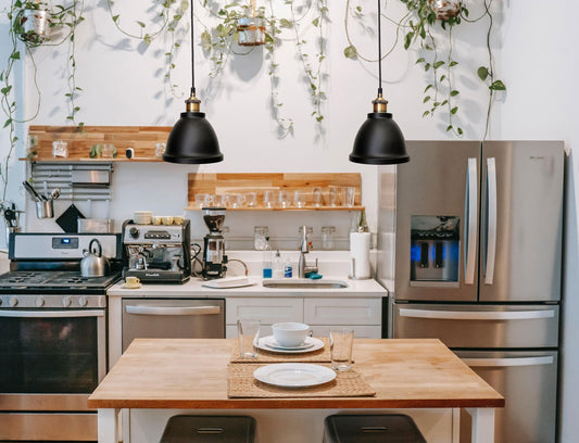 Two black pendant lights with brass details hanging above a kitchen table