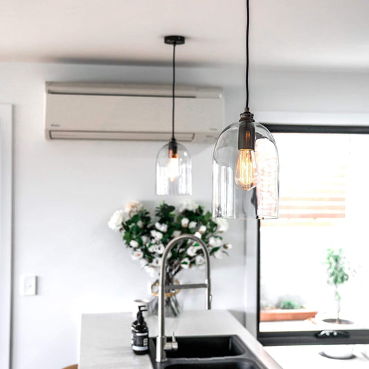 Clear dome glass pendant light with black socket and visible glowing bulb