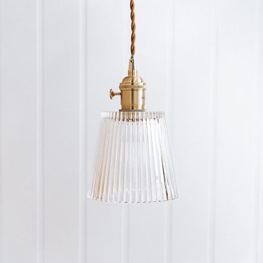 Vintage glass pendant light with clear ribbed shade and brass socket, hanging on braided cord