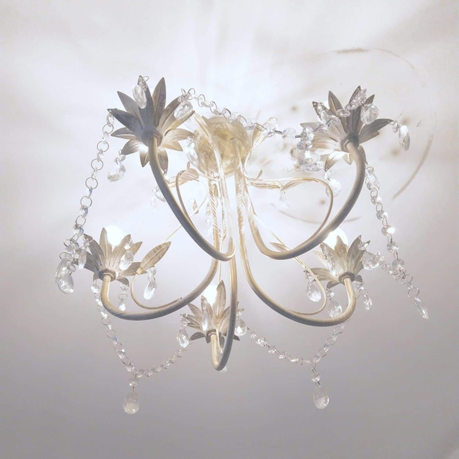 White leaf chandelier with crystal teardrop chains, curved arms, and candle-style bulbs