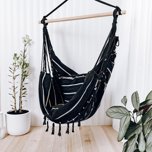 Black rope-hung hammock chair with fringe and striped seat cushion