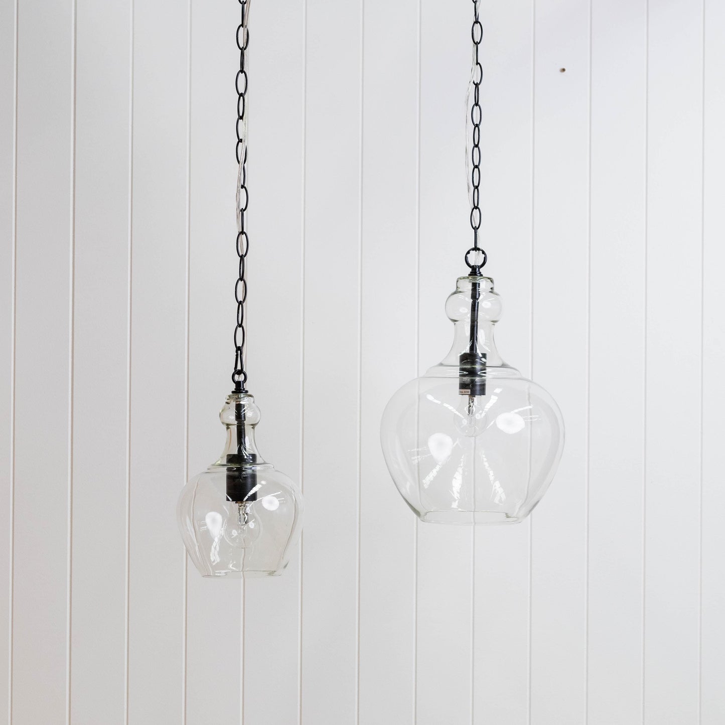 Glass globe pendant light pair on black chain, clear round shades with metal caps