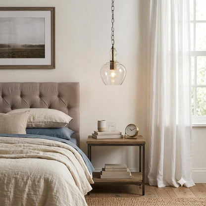 Single antique brass pendant light with clear bell-shaped glass shade on chain