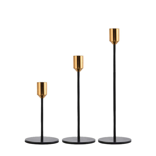Three black taper candlesticks with brass cup tops and round bases