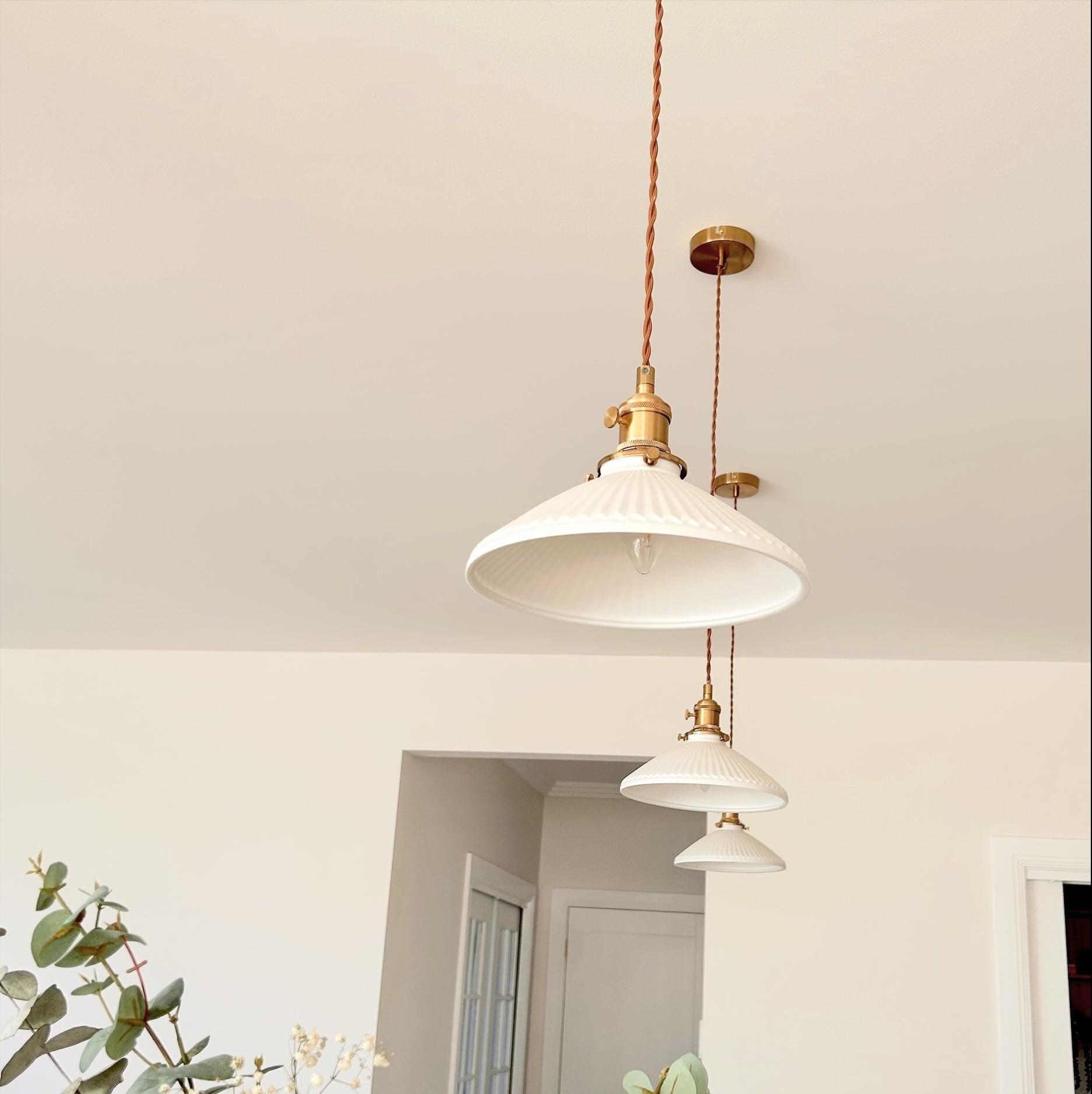 Cluster of ceramic pleated pendant lights with white shades and braided cord brass mounts