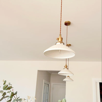 Cluster of ceramic pleated pendant lights with white shades and braided cord brass mounts
