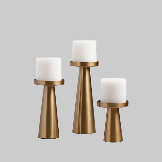 Set of three brushed brass candle holders with white pillar candles, tall and short