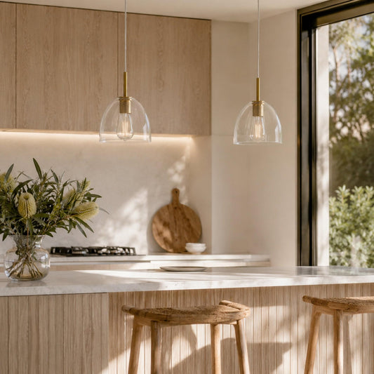 Pair of gold pendant lights with clear glass shades and brass caps, suspended on cords