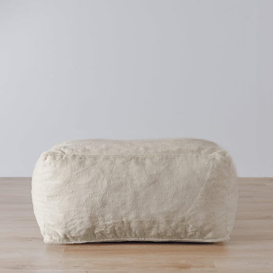 DreamPod® ottoman in champagne-colored plush fabric, rounded rectangular shape.