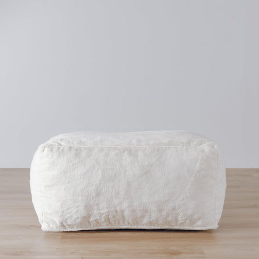 White upholstered ottoman with rounded corners and plush textured fabric