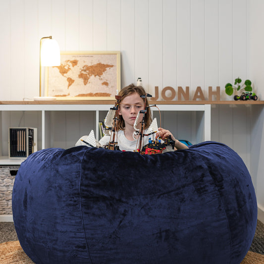 Navy blue round bean bag, plush upholstery with curved stitched seams