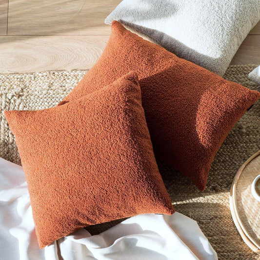 Rust boucle teddy cushion cover with insert, angled view on cushions and rug