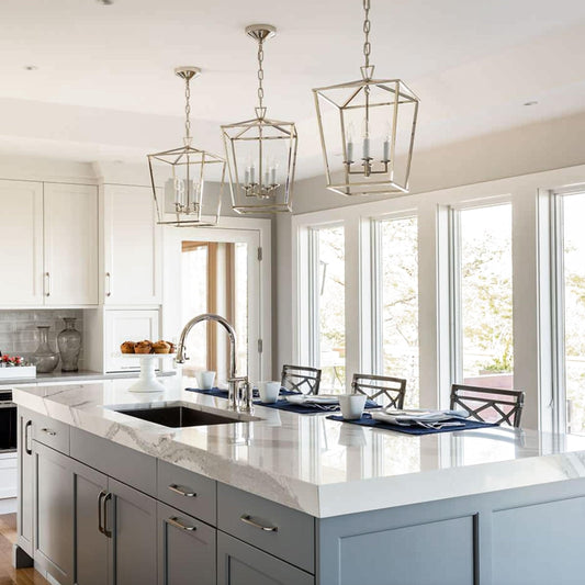 Multiple brushed chrome cage pendant lights with candle-style bulbs in a kitchen