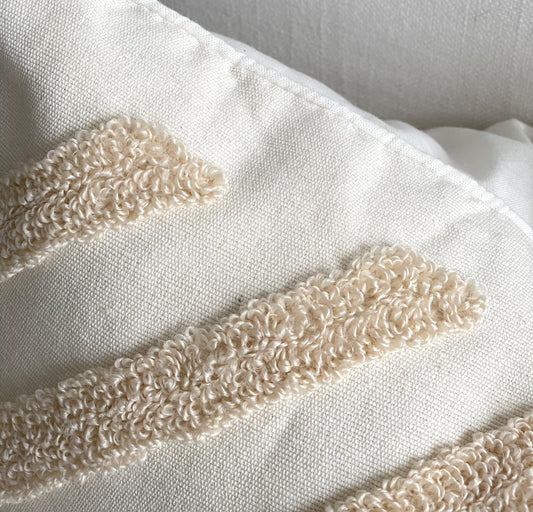 Tufted cushion cover with curved loop trim detail in cream