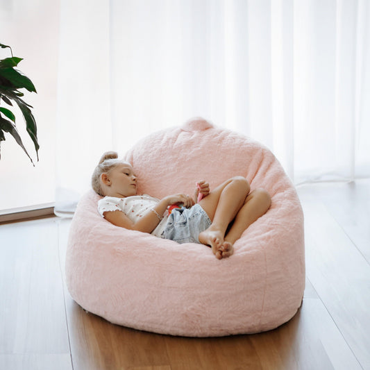 Soft pink mini beanbag chair with plush fabric, child lounging inside.
