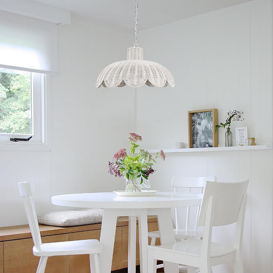 White rattan scallop pendant light with hanging chain over dining table