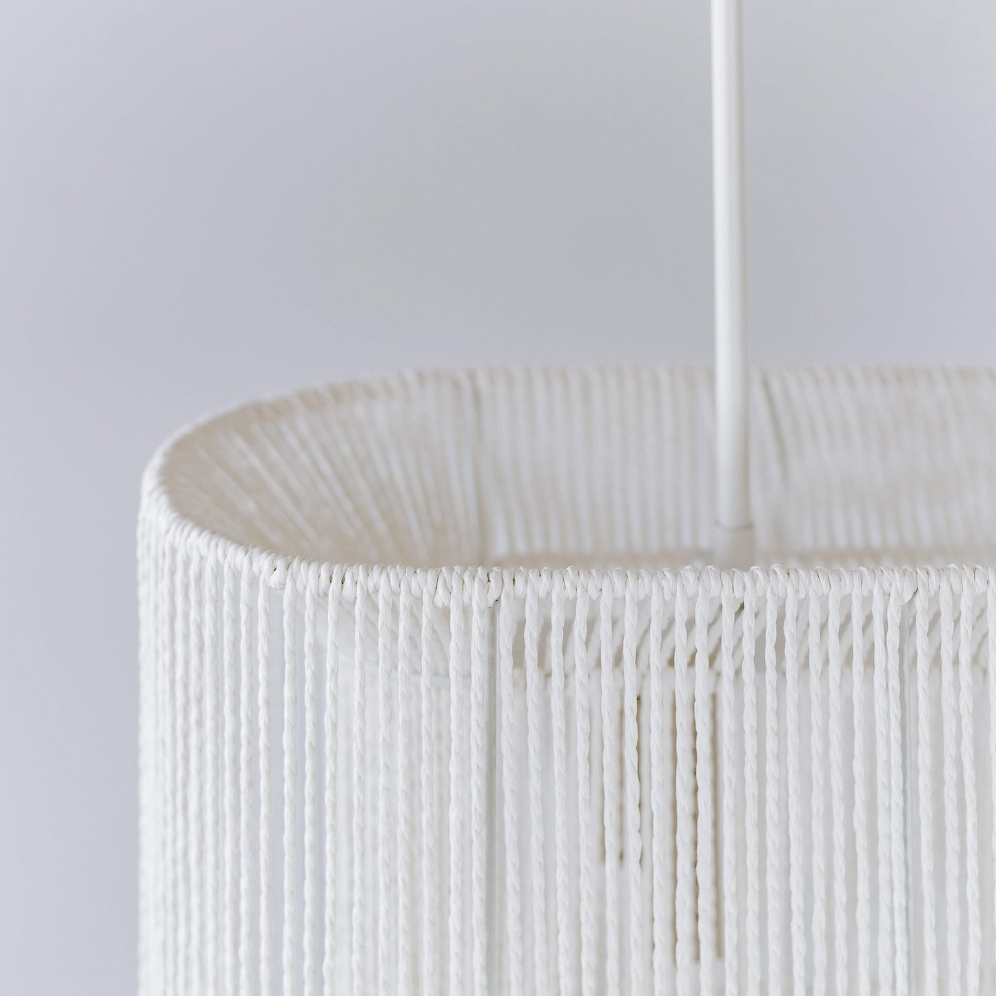White rope pendant shade close-up with woven vertical strands and cord hanger