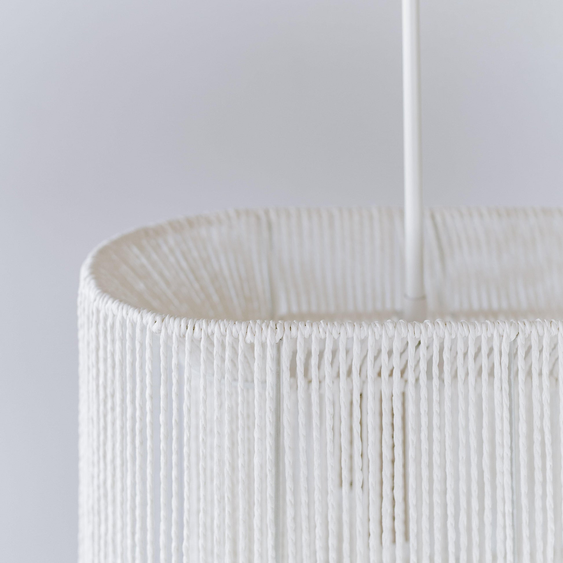 White rope pendant shade close-up with woven vertical strands and cord hanger
