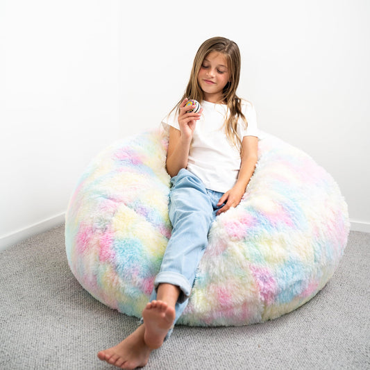 Rainbow tie-dye faux-fur bean bag with a child seated on the soft shag surface