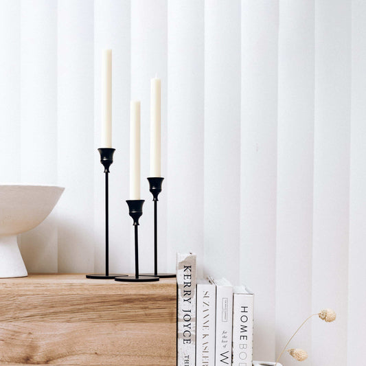 Black 3-piece candlestick set with three taper holders holding white taper candles.