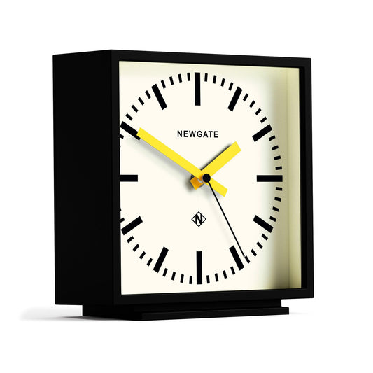 Black mantel clock with cream dial, Newgate logo, yellow hands in angled view