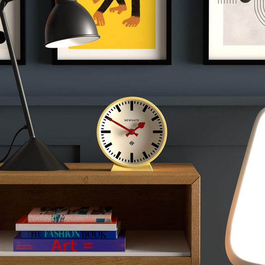 Yellow mantel clock on shelf with white dial, black Roman numerals, red hands