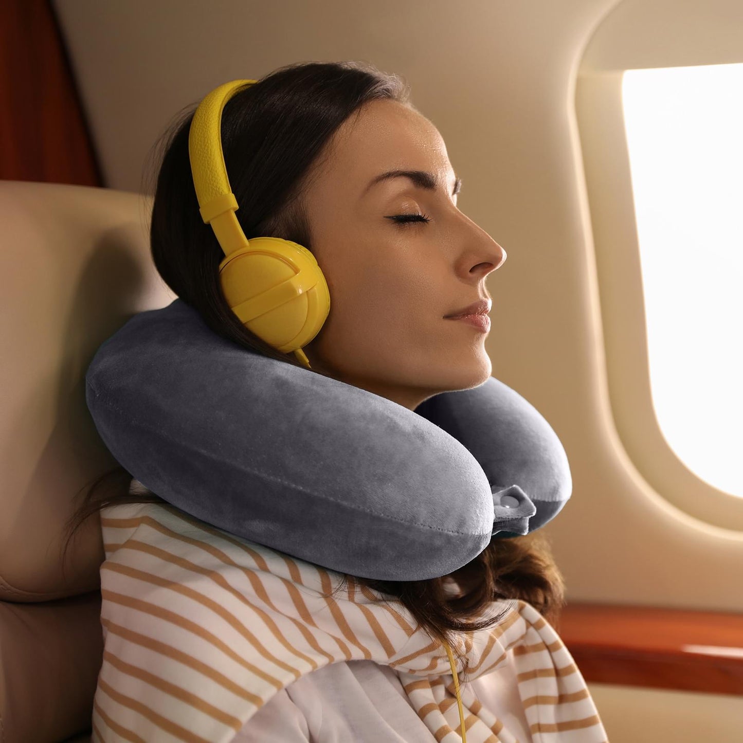 Grey travel neck pillow with memory foam worn around neck on airplane seat