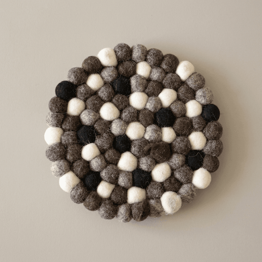 Round wool felt trivet with pebble spheres, dark charcoal and cream pattern