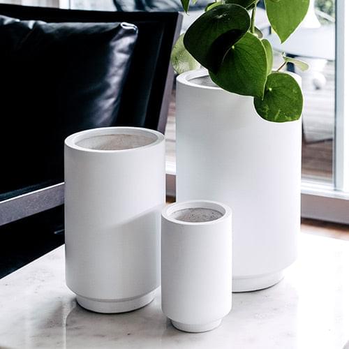 White cylindrical planter set with three matching pots and flared top rims.