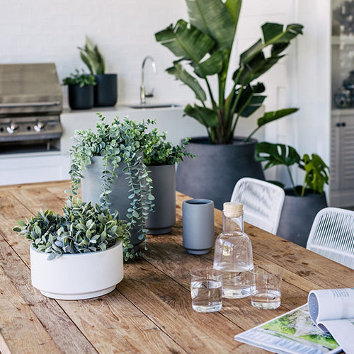 Blue-gray and white cylindrical planter set with three pots on a wooden table.