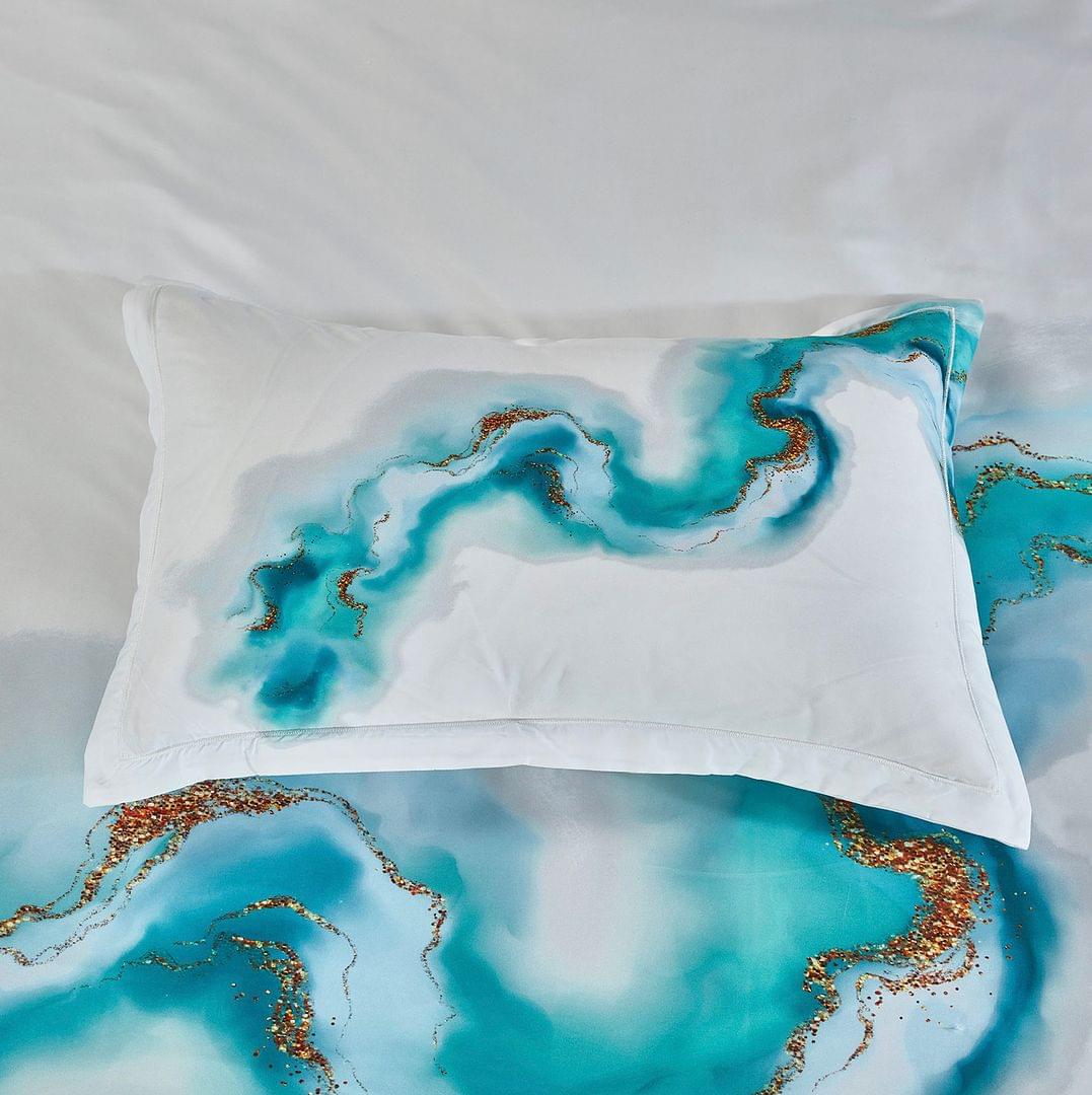 White pillow sham with teal and gold marble-like swirl pattern