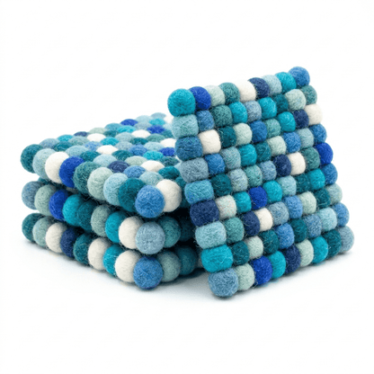 Round wool felt coaster with layered pom-pom texture in teal, navy, and cream
