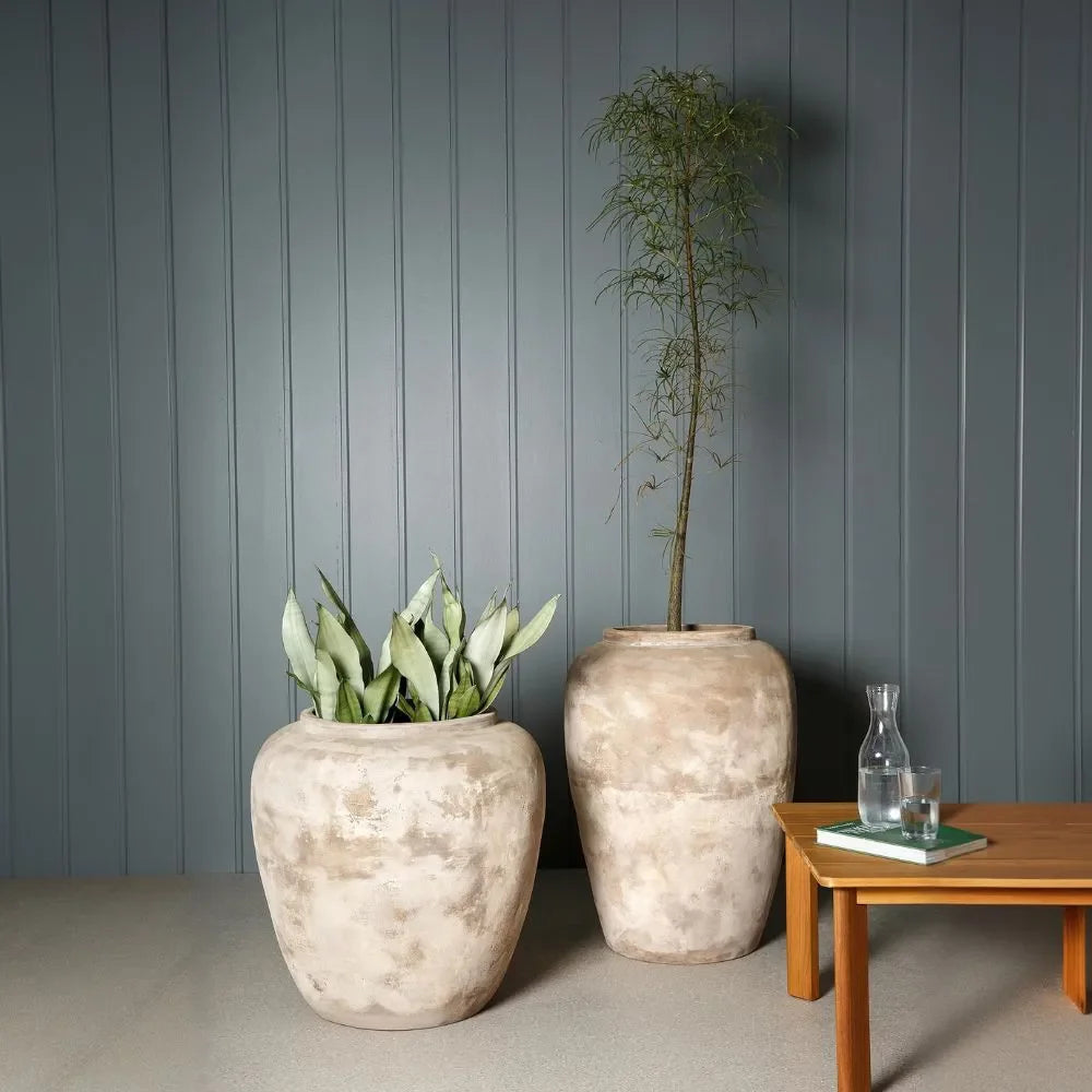 Two stone-textured planter jars on a table, rounded off-white mottled finish.