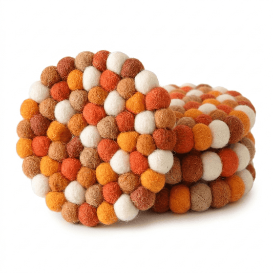 Round wool felt coaster with colorful pom-pom balls in orange, white, and tan