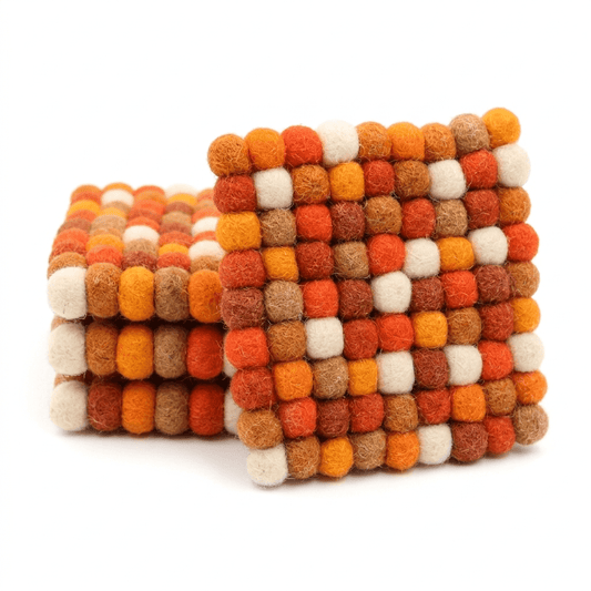 Square wool felt coaster with stacked pom-pom blocks in orange, white, and tan