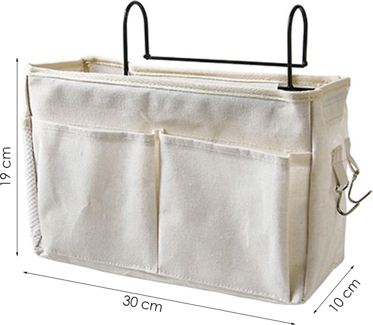 White cotton bedside pocket organizer with frame, three compartments, and hanging hooks