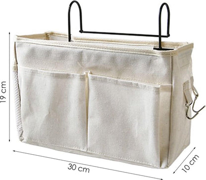 White cotton bedside pocket organizer with frame, three compartments, and hanging hooks