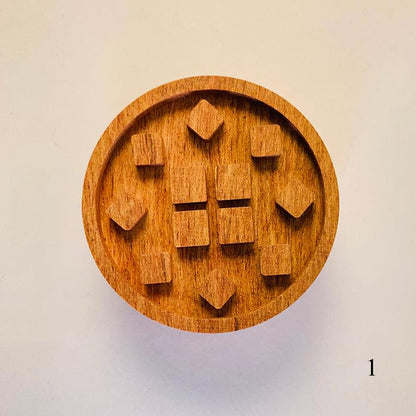 Round wooden diffuser lid with centered geometric block cutouts and tan wood grain