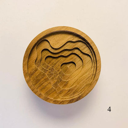 Round wooden diffuser lid with carved wavy lines and abstract animal profile